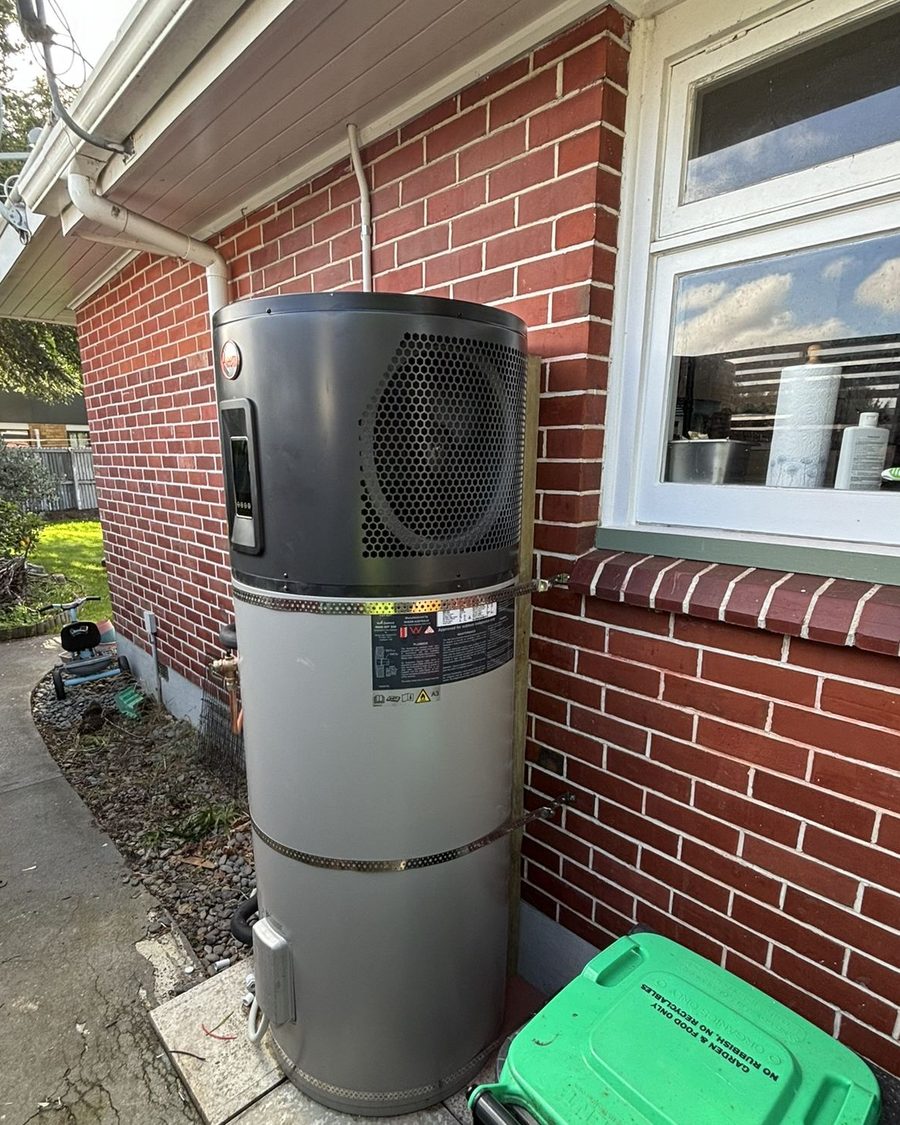 Hot water heat pump installed beside a brick home